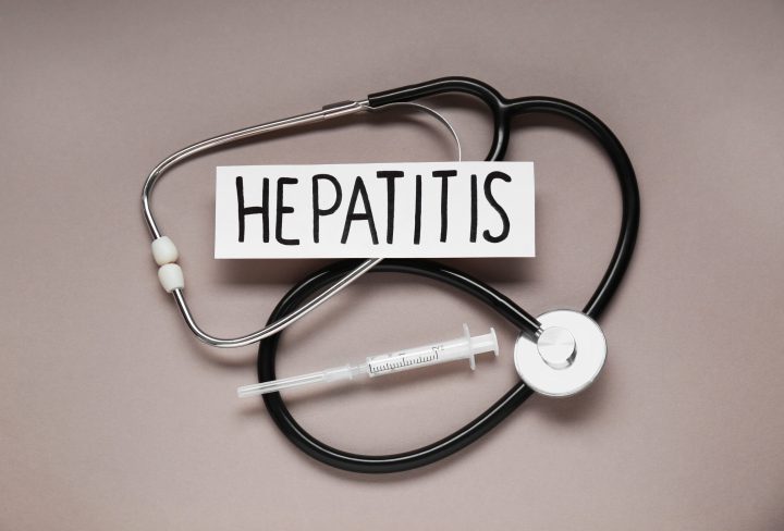 Word Hepatitis, stethoscope and syringe on beige background, flat lay